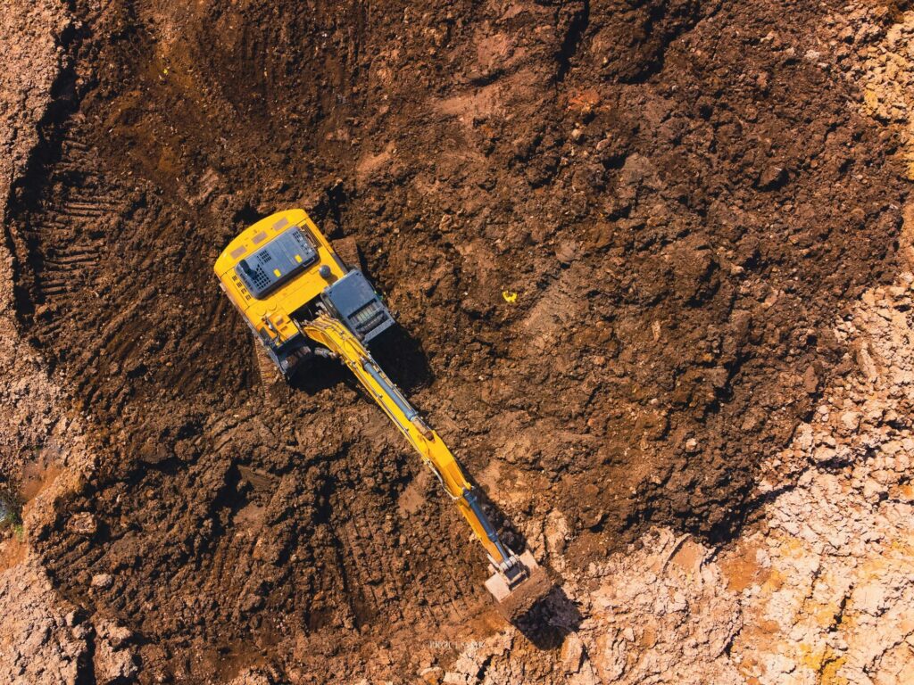 a large, articulated excavator digs through a pit of earth near
